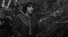 A woman stands in a forest.
