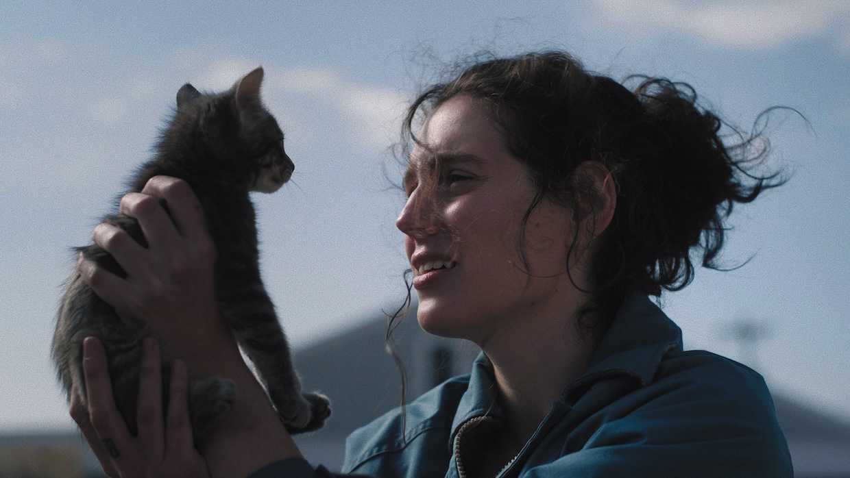 A woman holds a cat while standing outside.