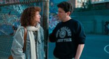 A man and a woman talk to each other outside of a basketball court.