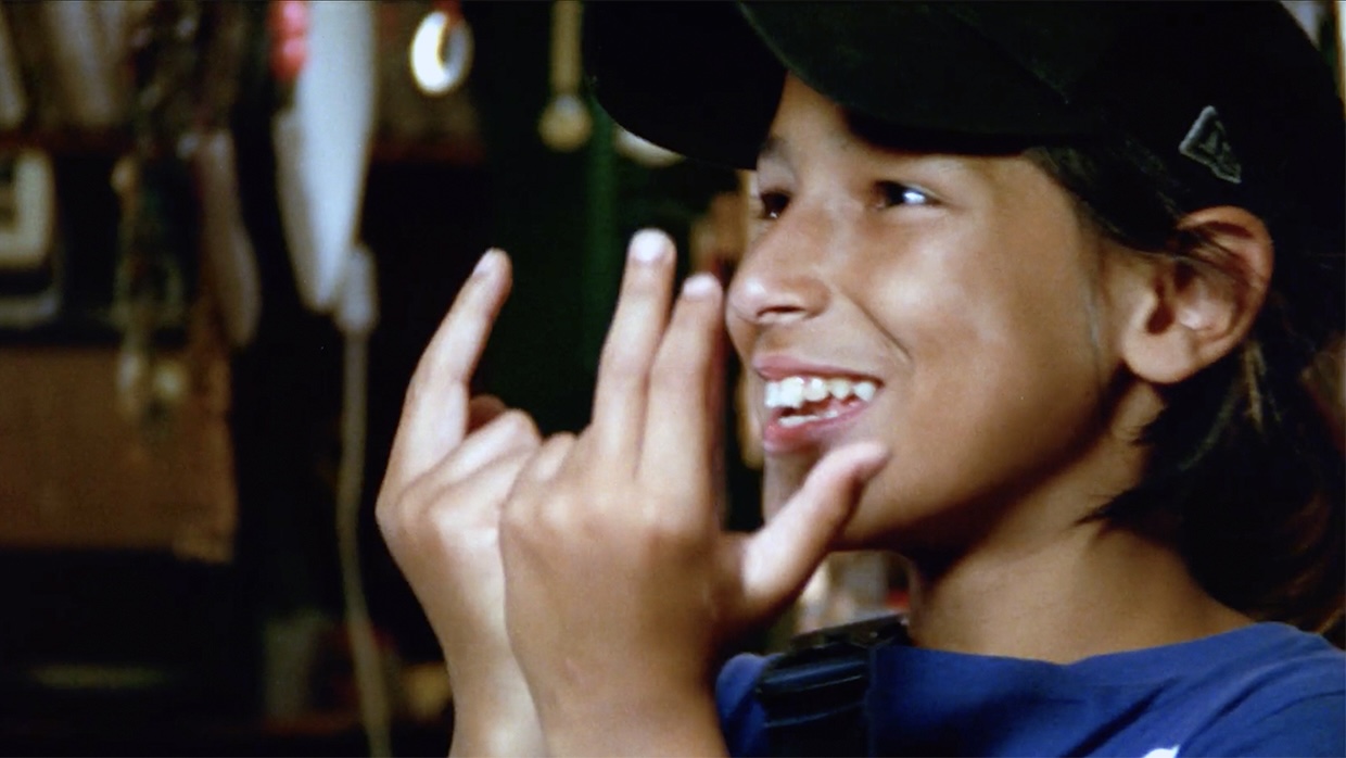 A young boy holds his hands and makes signs.