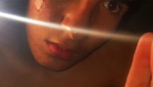 A teenager stares into the bright light of a cellphone.