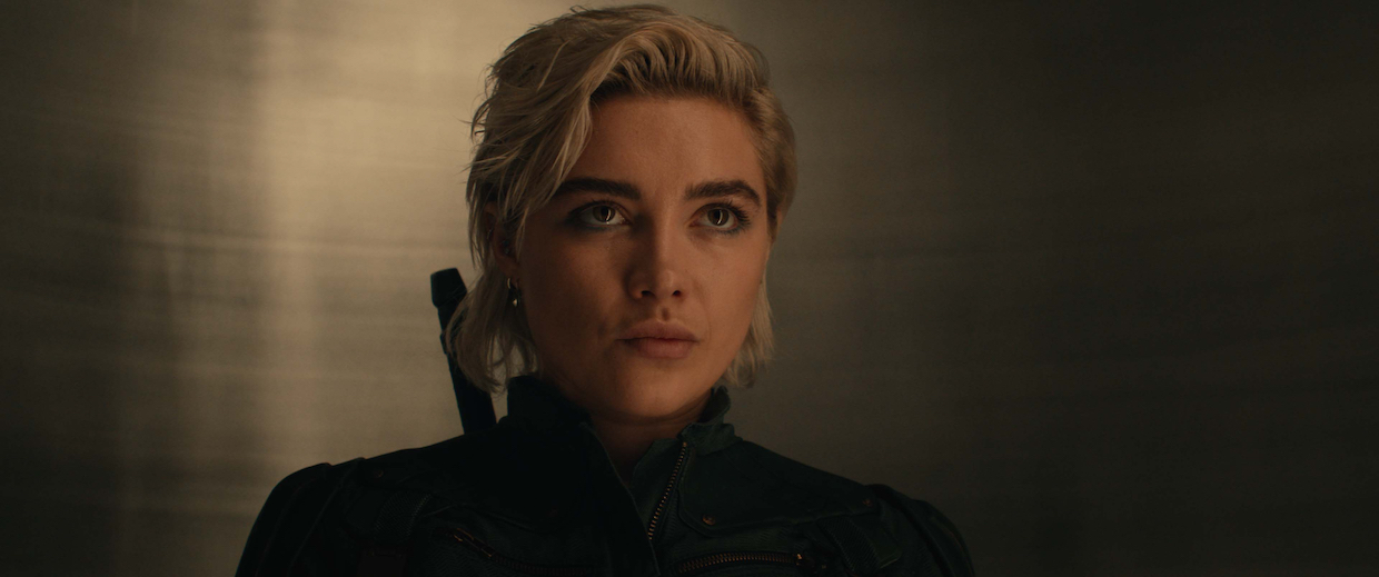 A blond woman in a black top in an unclear space.