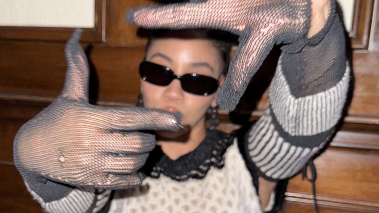 A woman performs the "framing a shot" hand pose.