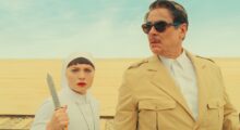 A woman holding a knife and a man in a desert.