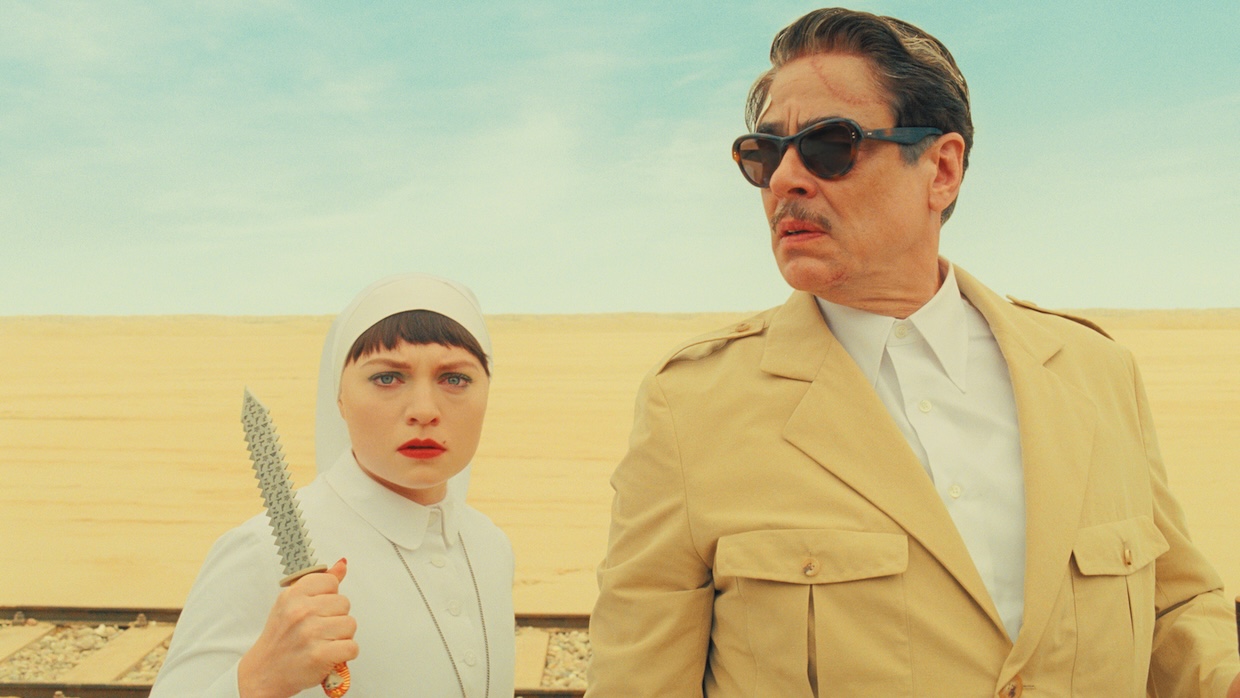 A woman holding a knife and a man in a desert.