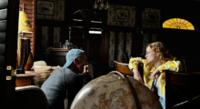 A man and a woman sit in a room and talk.