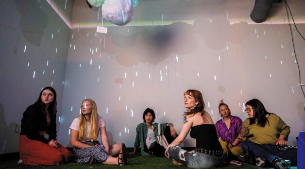 A group of students sit in a multimedia space.