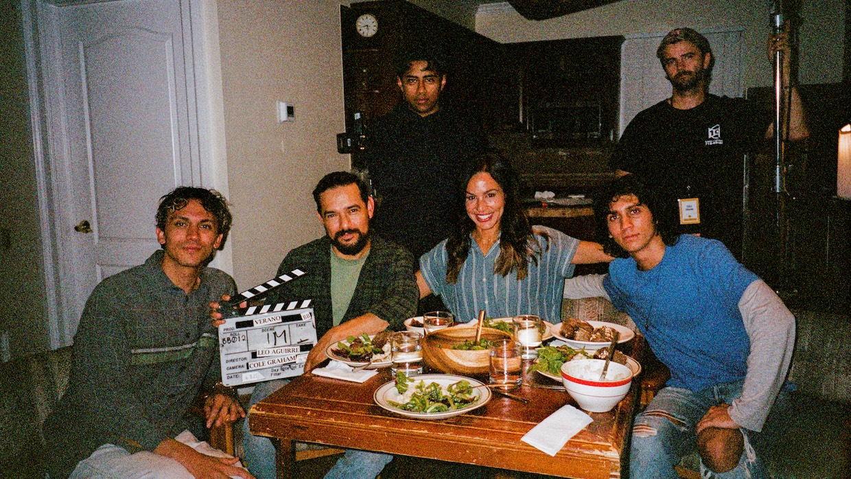 A group of people around a table holding a clapboard.