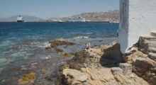 Two people on a rocky beach shore in Greece.