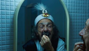 A man examines his fangs in a mirror.