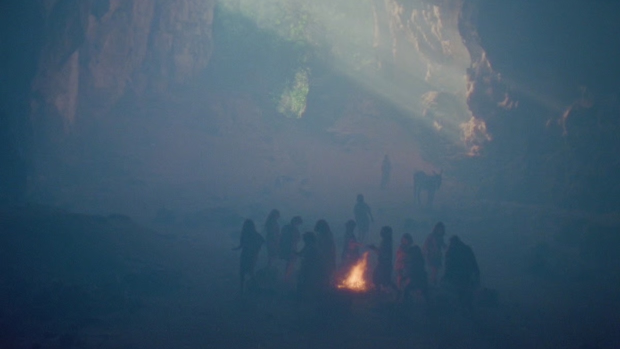 Children cluster around a small fire in a smoggy quarry.