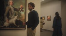 A man stands in front of a painting in a museum.