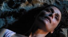 A woman lies on a beach at night.