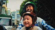 A girl and a woman on a moped.
