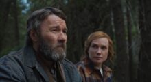 A man and a woman sit in a forest.