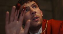 A red-robed priest holds up a bloody hand.