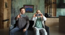 Two men with iPhones sit in chairs.