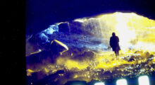 A saturated image in deep blues and yellows depicting a shadowy figure surrounded by ice.