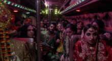 Pakistani wedding guests sit in a party bus decked-out in colorful traditional garb.