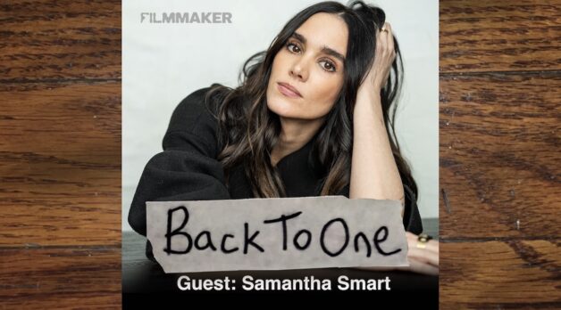 Headshot of actress Samantha Smart, who has long brown hair and leans her head against her hand.
