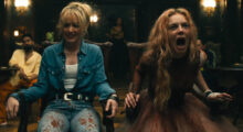 Two blonde women, one wearing jeans, a white tee and a denim shirt, the other a bloodied wedding dress, scream while tied to chairs.