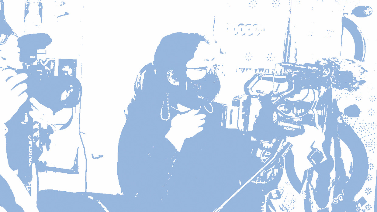A blue and white image of a woman wearing a face mask and shooting with a digital film camera.