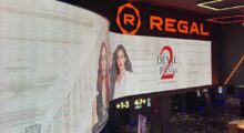 A long, waving LED screen that contains a promo image for 'The Devil Wears Prada 2' featuring Emily Blunt and Anne Hathaway.