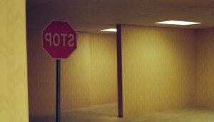 A stop sign reads backwards in a dingy, yellow hallway with many corridors.